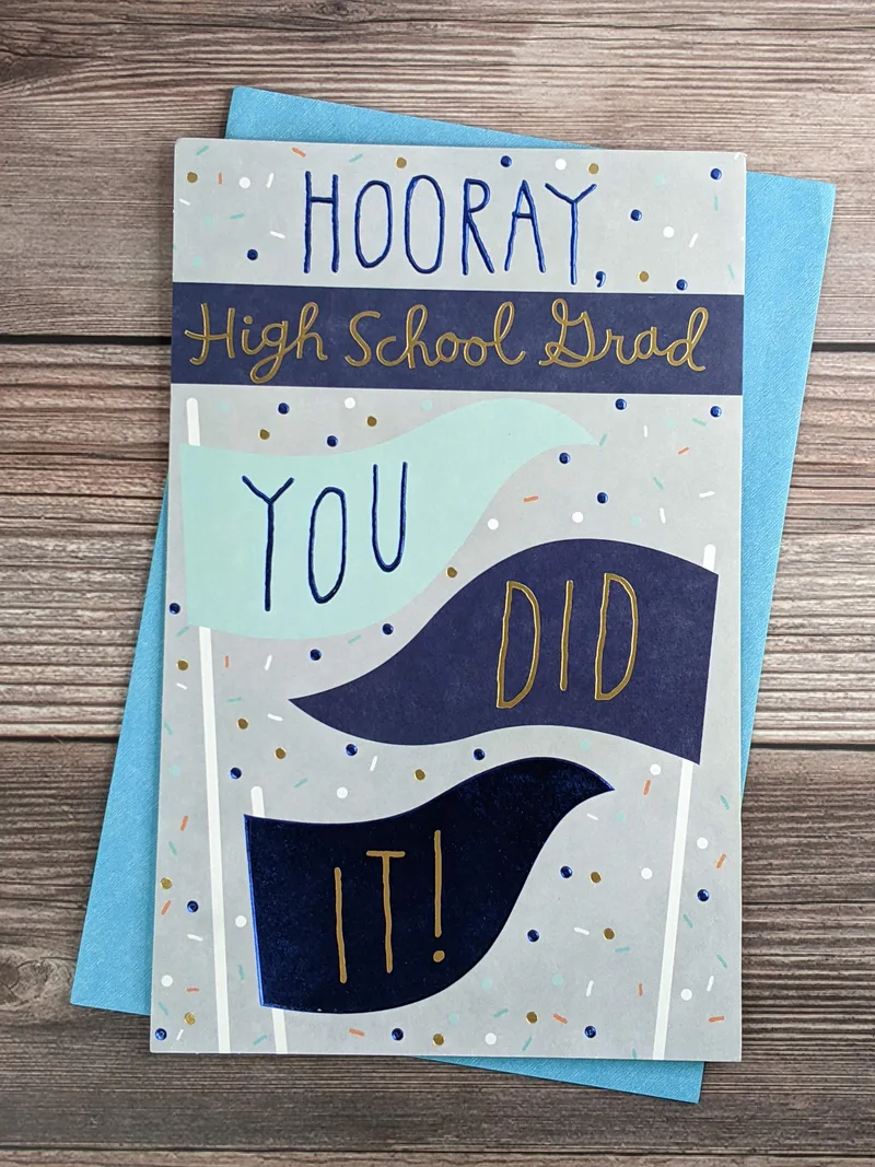 A high school graduation greeting card with a gray cover featuring blue banners saying, "You did it!"