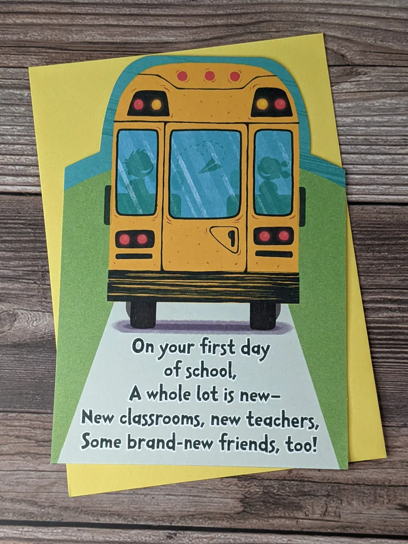 A first-day-of-school greeting card for a child with an image of a yellow school bus on the front cover.