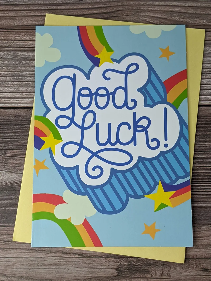 A greeting card for back-to-school that has "Good Luck" on the front blue cover with images of shooting stars and rainbows.
