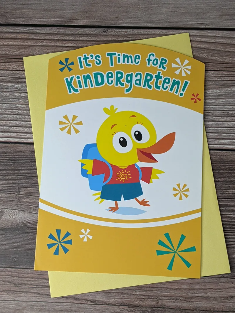 A back-to-school greeting card for a kindergartener with a yellow duck wearing a blue backpack on the front cover.
