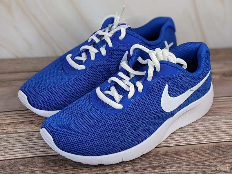 A pair of youth sized blue Nike running shoes with a white swoosh and laces.