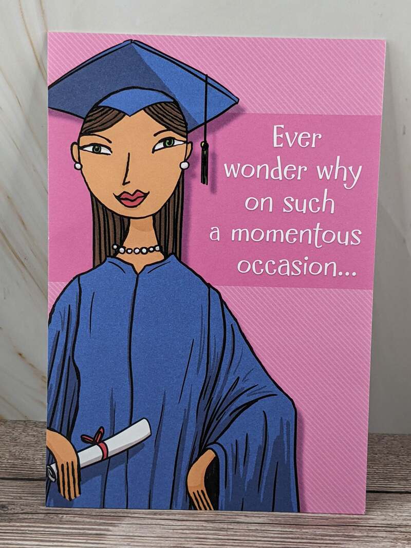 A pink graduation greeting card with an image of a young woman with a blue graduation gown and cap.